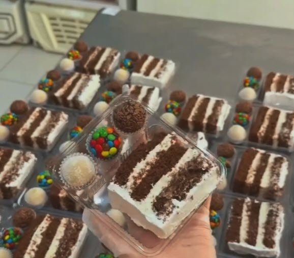 bandejinha transparente com fatia de bolo de chocolate e docinhos formando um kit de festa infantil individual