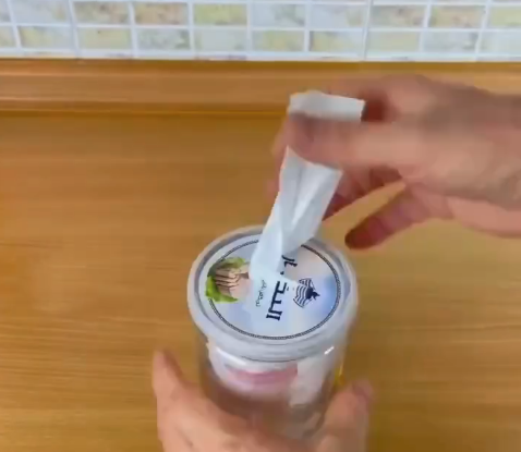 pote plástico com tampa recortada funcionando como dispenser para organizar sacolas plásticas dobradas