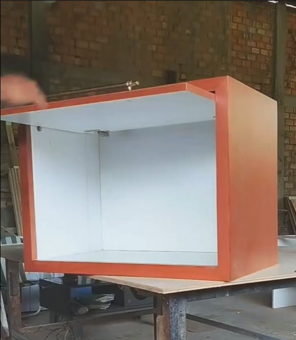 armário laranja e branco com porta basculante aberta usando duas corrediças laterais fixadas nas paredes internas